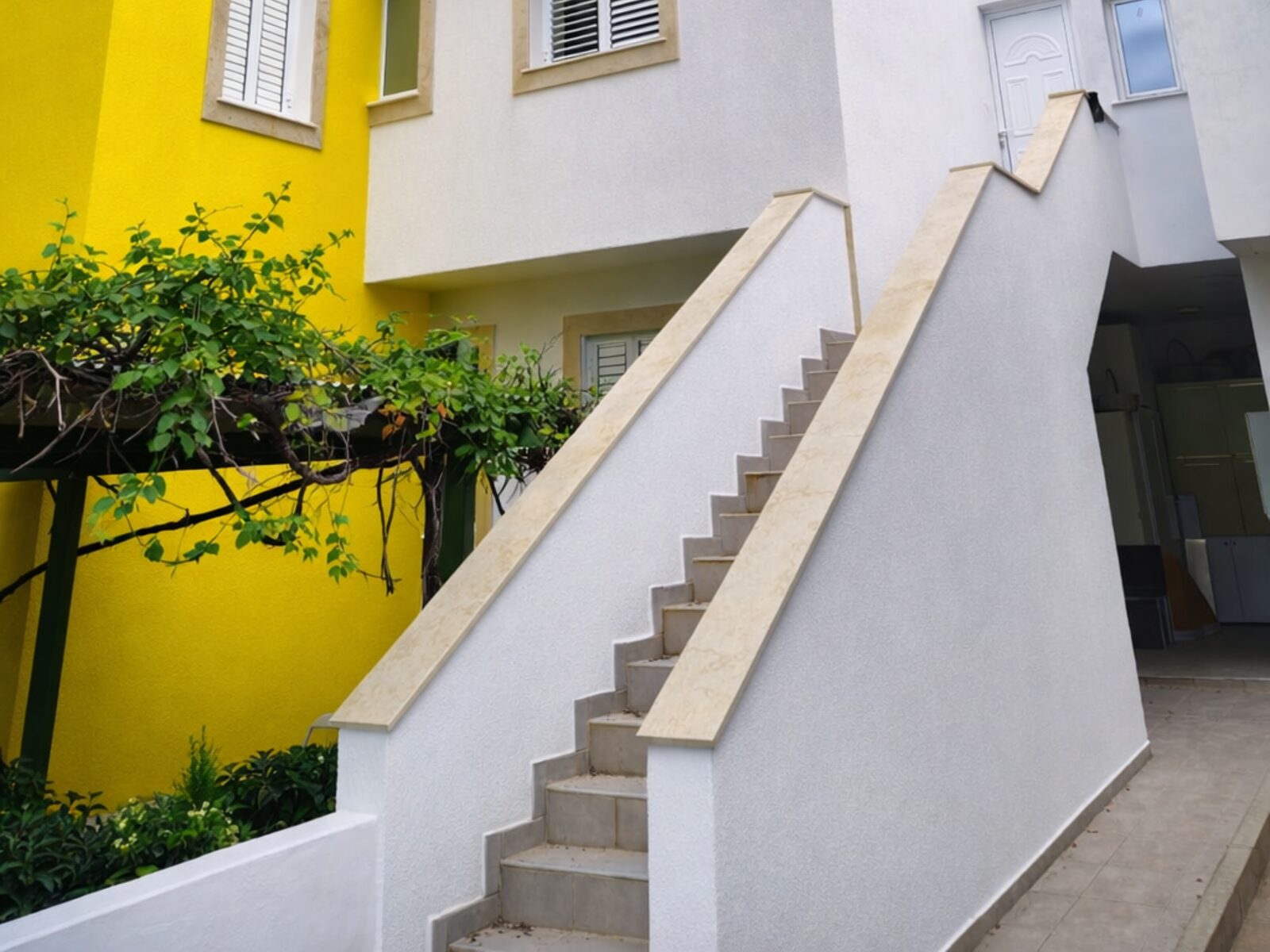 Pervolia building exterior after renovation, finished staircase and vine pergola